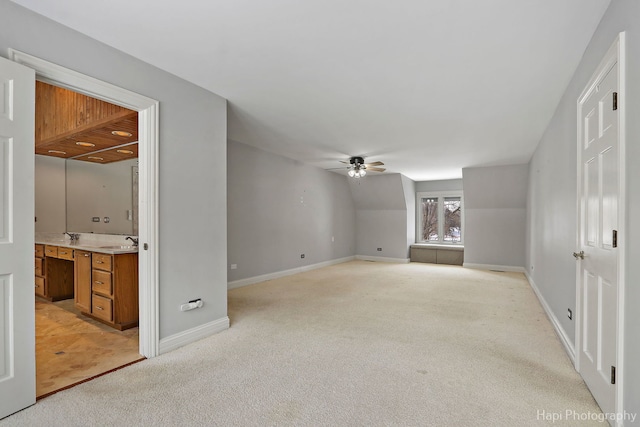 interior space featuring baseboards, a ceiling fan, and light colored carpet