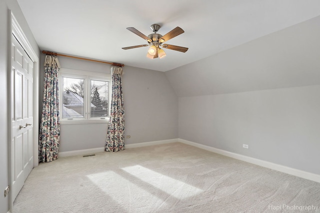 additional living space with lofted ceiling, light carpet, a ceiling fan, visible vents, and baseboards