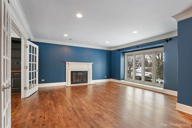 unfurnished living room featuring dark wood-type flooring, baseboards, ornamental molding, french doors, and a glass covered fireplace