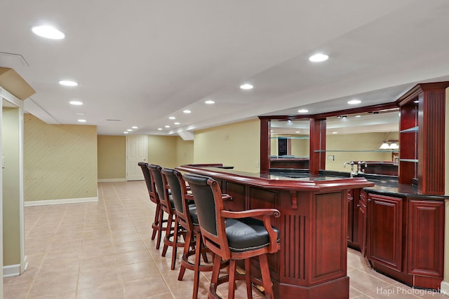 bar with light tile patterned floors, baseboards, indoor wet bar, and recessed lighting