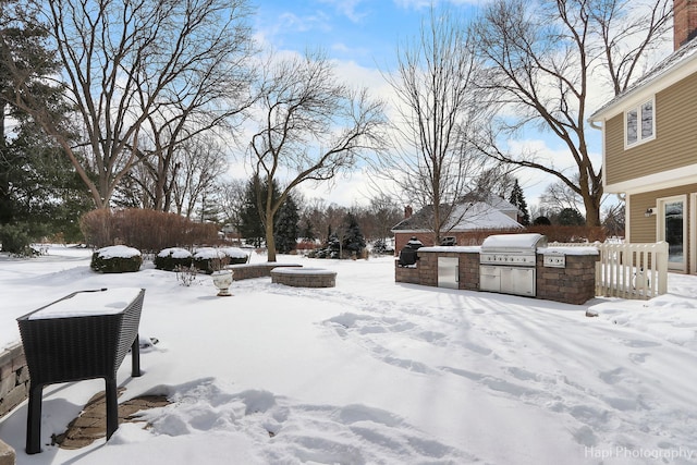 yard layered in snow featuring a fire pit and exterior kitchen