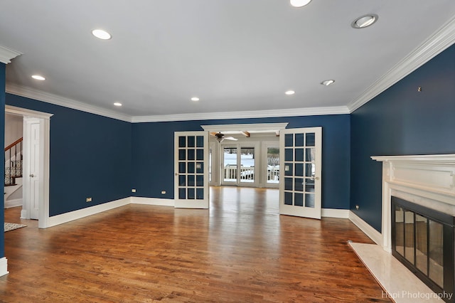 unfurnished living room featuring a fireplace, wood finished floors, ornamental molding, french doors, and stairway