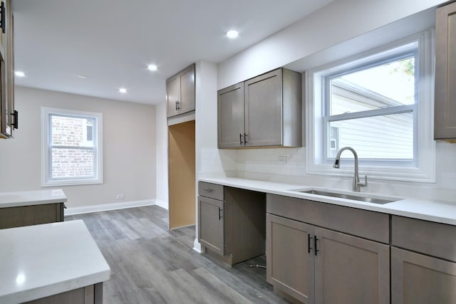 kitchen with tasteful backsplash, sink, and light hardwood / wood-style flooring