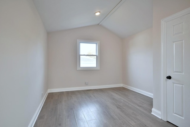 additional living space featuring vaulted ceiling and light hardwood / wood-style flooring