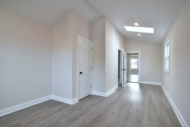 interior space featuring vaulted ceiling with skylight and hardwood / wood-style floors