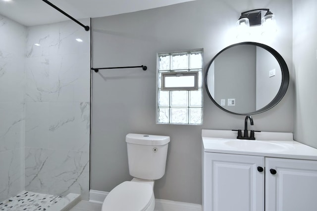 bathroom with vanity, toilet, and tiled shower