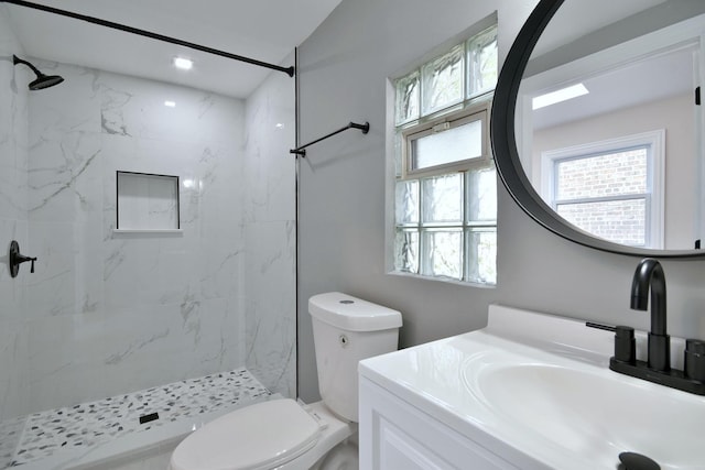 bathroom featuring vanity, a tile shower, and toilet