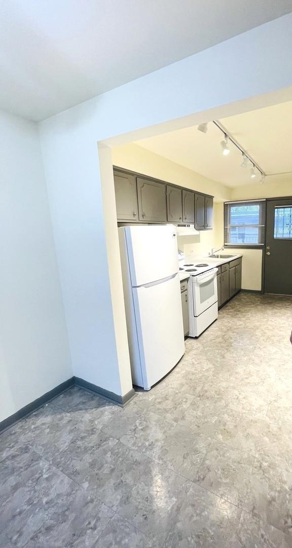 kitchen with rail lighting, sink, and white appliances