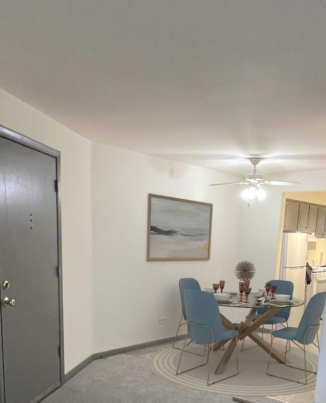 carpeted dining space with ceiling fan and a textured ceiling