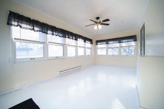 empty room featuring a baseboard heating unit, concrete floors, and ceiling fan