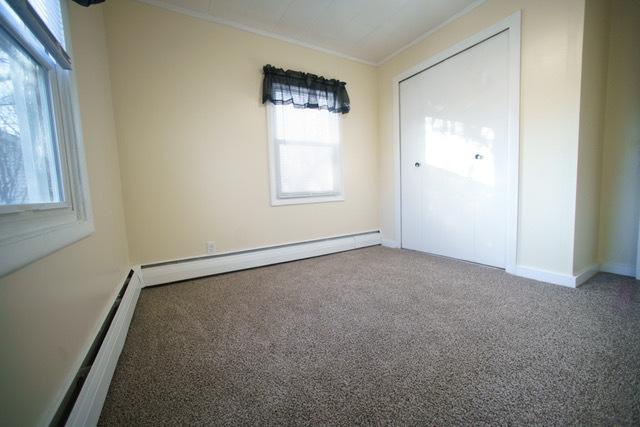 carpeted spare room featuring baseboard heating