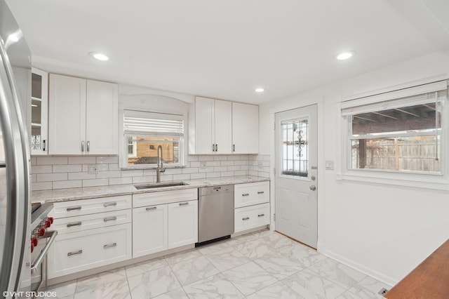 kitchen with sink, white cabinetry, tasteful backsplash, stainless steel appliances, and light stone countertops