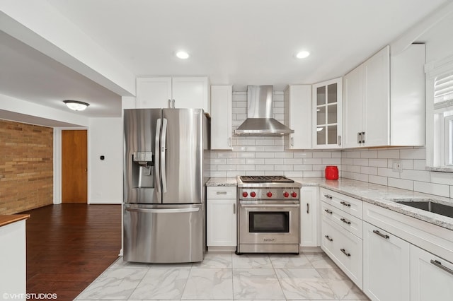 kitchen with wall chimney exhaust hood, appliances with stainless steel finishes, and white cabinets