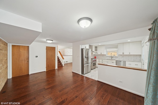 kitchen featuring sink, white cabinetry, tasteful backsplash, appliances with stainless steel finishes, and kitchen peninsula