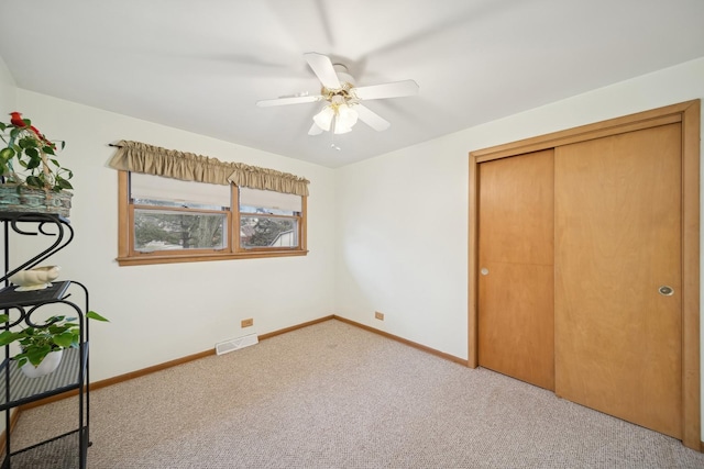 unfurnished bedroom featuring light colored carpet, a closet, and ceiling fan