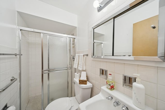 bathroom featuring toilet, sink, tile walls, and a shower with shower door