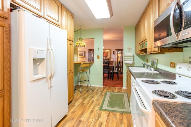 kitchen featuring hanging light fixtures, white appliances, light hardwood / wood-style flooring, and sink