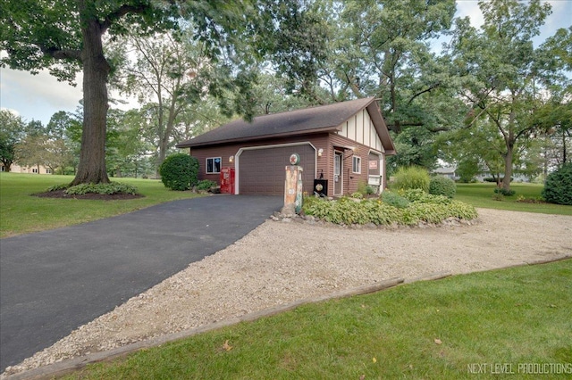 view of side of home featuring an attached garage, aphalt driveway, and a lawn