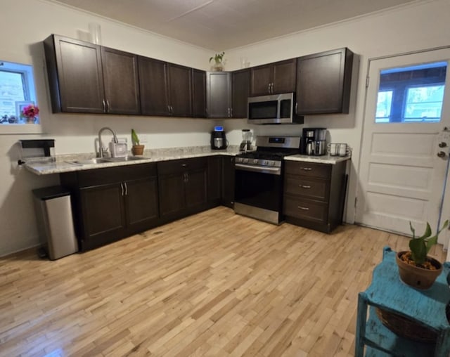 kitchen featuring sink, crown molding, dark brown cabinets, light hardwood / wood-style flooring, and appliances with stainless steel finishes