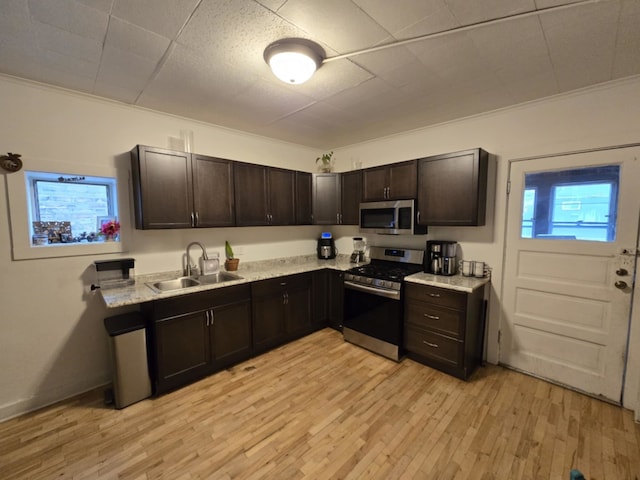 kitchen featuring light wood-type flooring, sink, dark brown cabinets, and appliances with stainless steel finishes