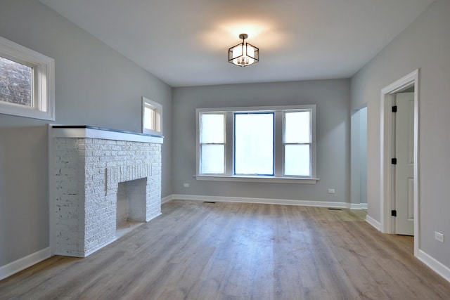 unfurnished living room with a fireplace and light hardwood / wood-style floors