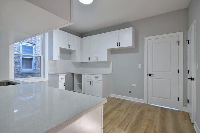 kitchen with white cabinetry, light stone countertops, backsplash, and light hardwood / wood-style floors