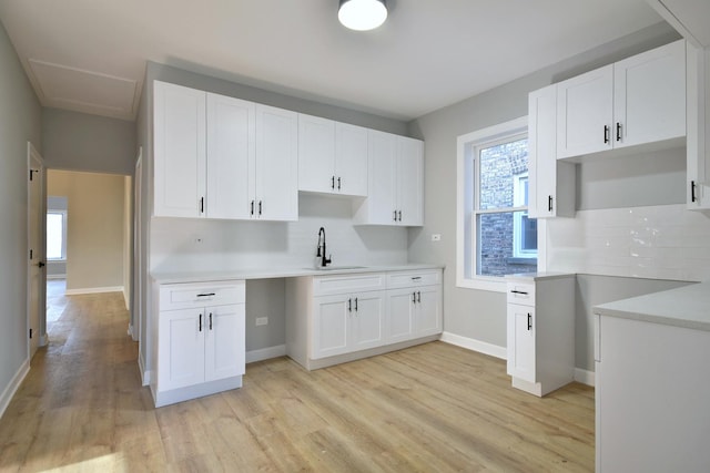 kitchen with tasteful backsplash, sink, white cabinets, and light hardwood / wood-style floors