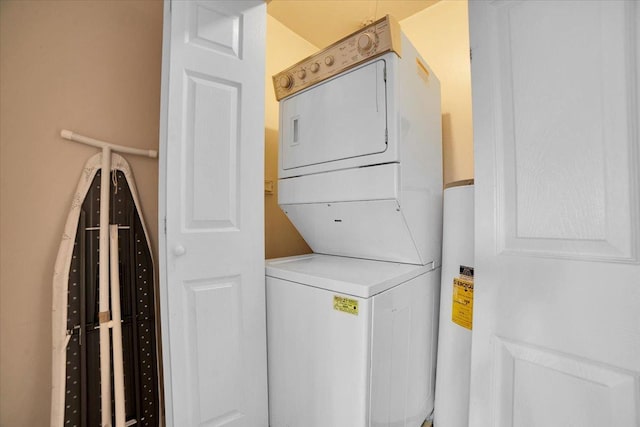 laundry room with stacked washer / drying machine and water heater