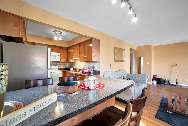 kitchen featuring backsplash, stainless steel fridge, light hardwood / wood-style floors, and a breakfast bar