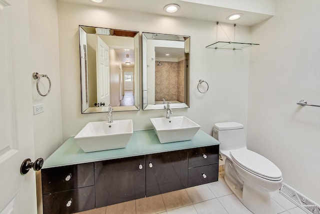 bathroom with vanity, toilet, tile patterned flooring, and a tile shower