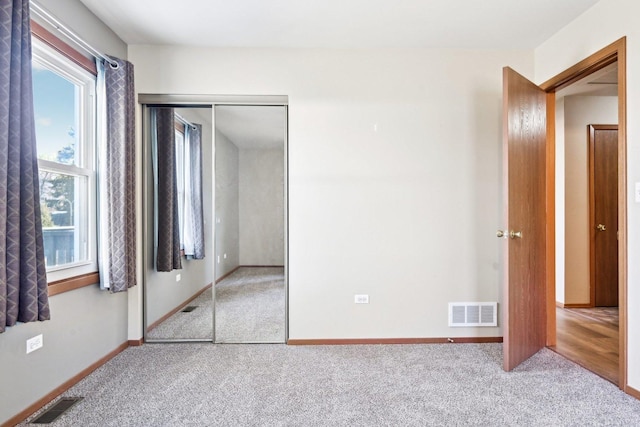 unfurnished bedroom featuring light carpet and a closet