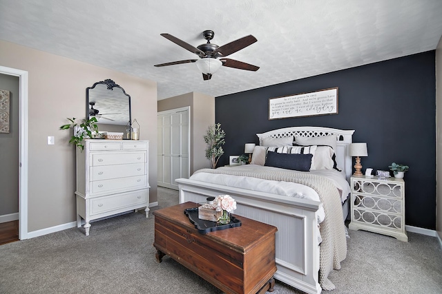 bedroom featuring a textured ceiling, a closet, ceiling fan, and dark colored carpet