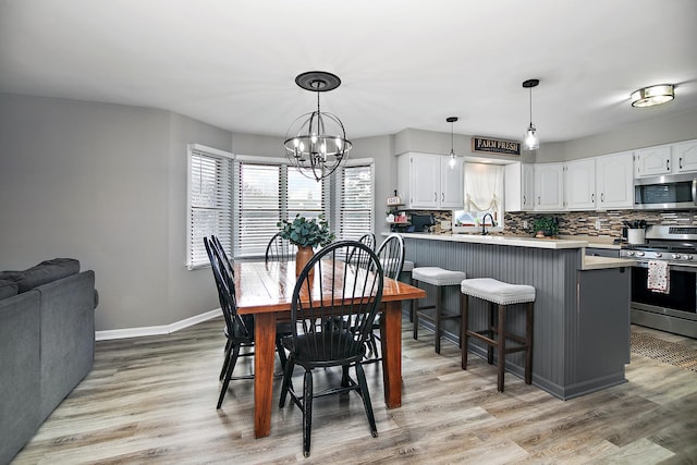 dining room featuring a notable chandelier, sink, and light wood-type flooring