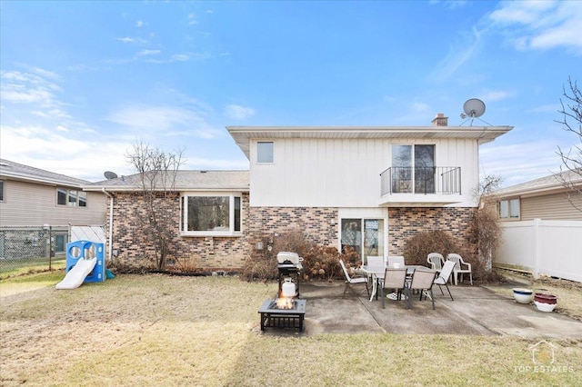 rear view of property with a yard, a patio area, a balcony, and an outdoor fire pit