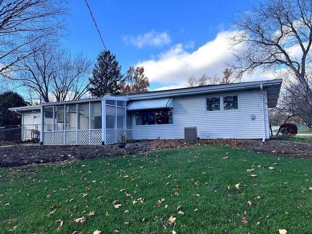 view of front of home featuring a sunroom, central air condition unit, and a front lawn