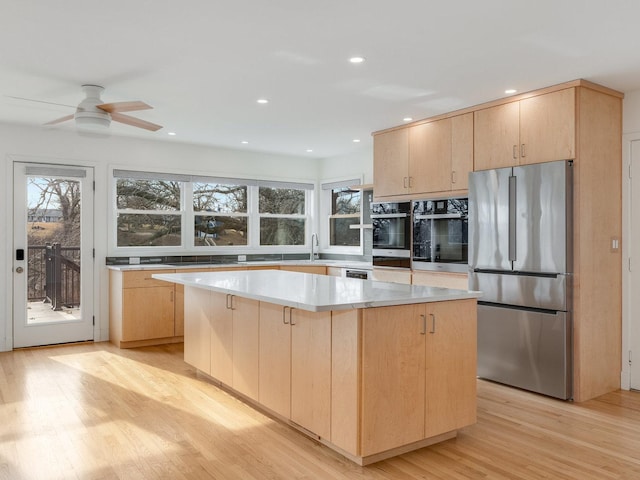 kitchen featuring stainless steel fridge, light hardwood / wood-style floors, a center island, and light brown cabinets