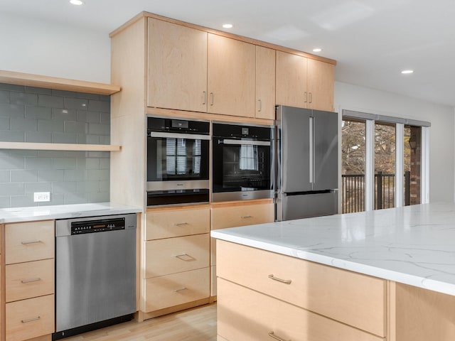 kitchen with light stone countertops, appliances with stainless steel finishes, light brown cabinets, and backsplash