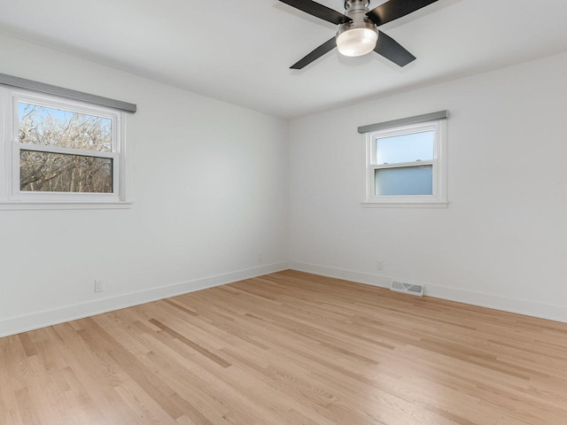 empty room with a wealth of natural light, light hardwood / wood-style floors, and ceiling fan