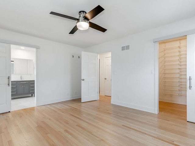 unfurnished bedroom featuring ensuite bath, sink, light hardwood / wood-style floors, and a closet