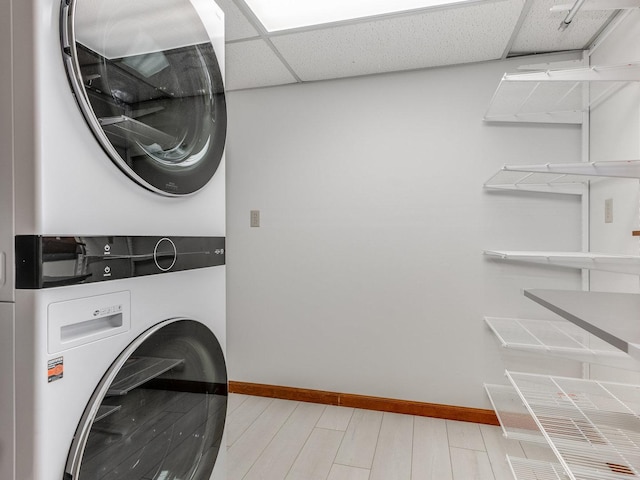 clothes washing area with light hardwood / wood-style flooring and stacked washer and clothes dryer