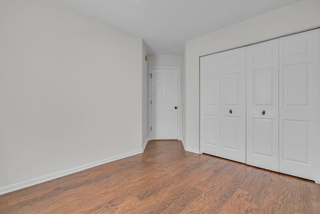 unfurnished bedroom with a closet and dark hardwood / wood-style floors