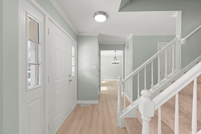 foyer entrance featuring crown molding, an inviting chandelier, and light hardwood / wood-style floors