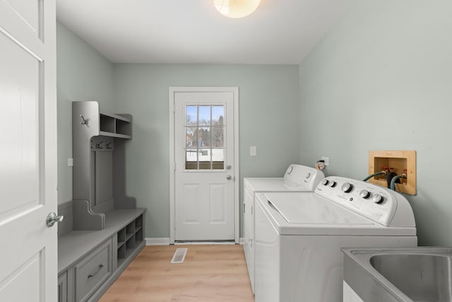 laundry room featuring sink, light hardwood / wood-style flooring, and washer and dryer