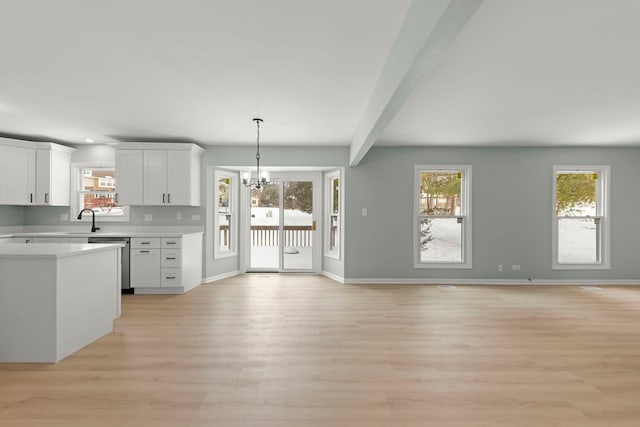 kitchen with pendant lighting, white cabinets, a chandelier, stainless steel dishwasher, and light wood-type flooring