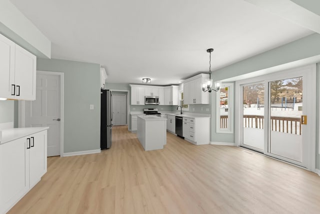 kitchen featuring light wood-type flooring, a kitchen island, pendant lighting, stainless steel appliances, and white cabinets