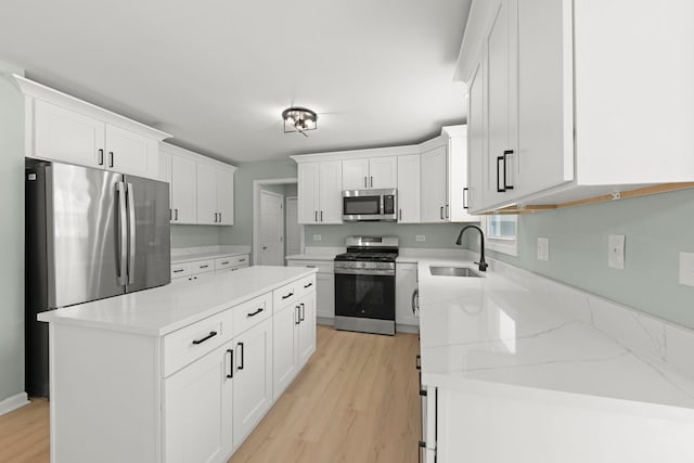 kitchen with sink, stainless steel appliances, a center island, and white cabinets