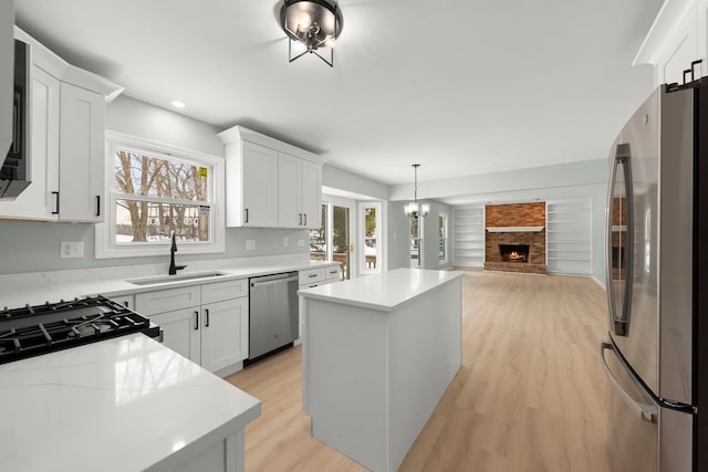 kitchen with a kitchen island, appliances with stainless steel finishes, sink, and white cabinets