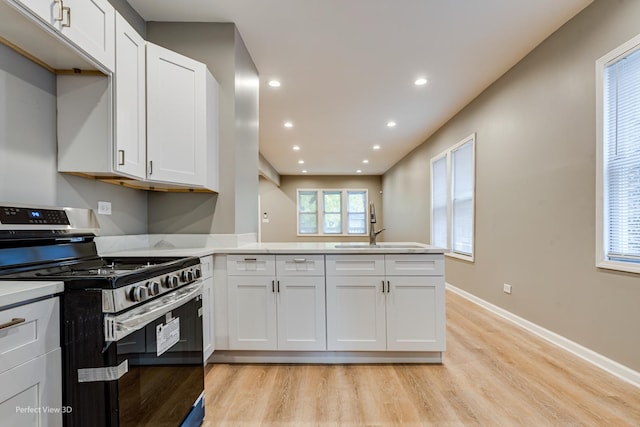 kitchen featuring sink, stainless steel stove, and white cabinets