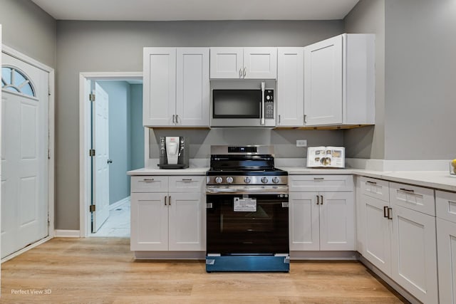 kitchen with stainless steel appliances, light hardwood / wood-style flooring, and white cabinets