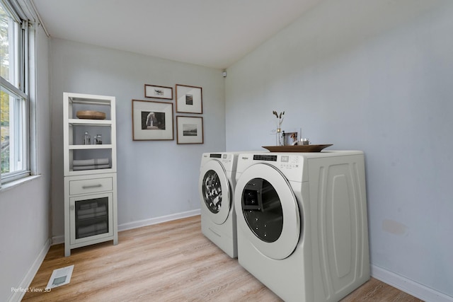 laundry area with light hardwood / wood-style floors and washing machine and clothes dryer